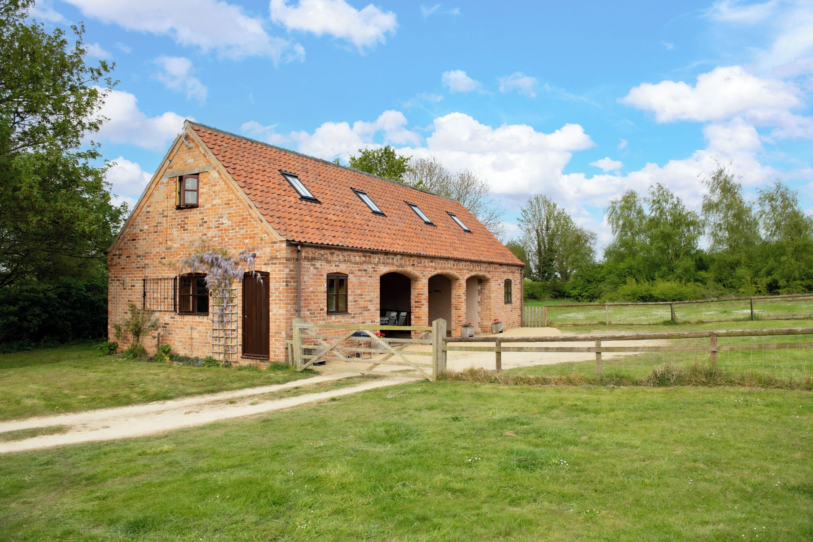 A brick building with a sloped roof, multiple windows, and a wooden gate.
