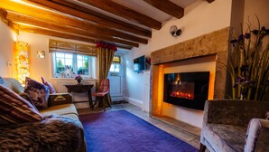 A cozy living room with a fireplace, wooden beams, a sofa, and a chair. - 'Oh So Snug' Bijou 1-bedroom cottage, in the heart of Whalley, Clitheroe  (Whalley)