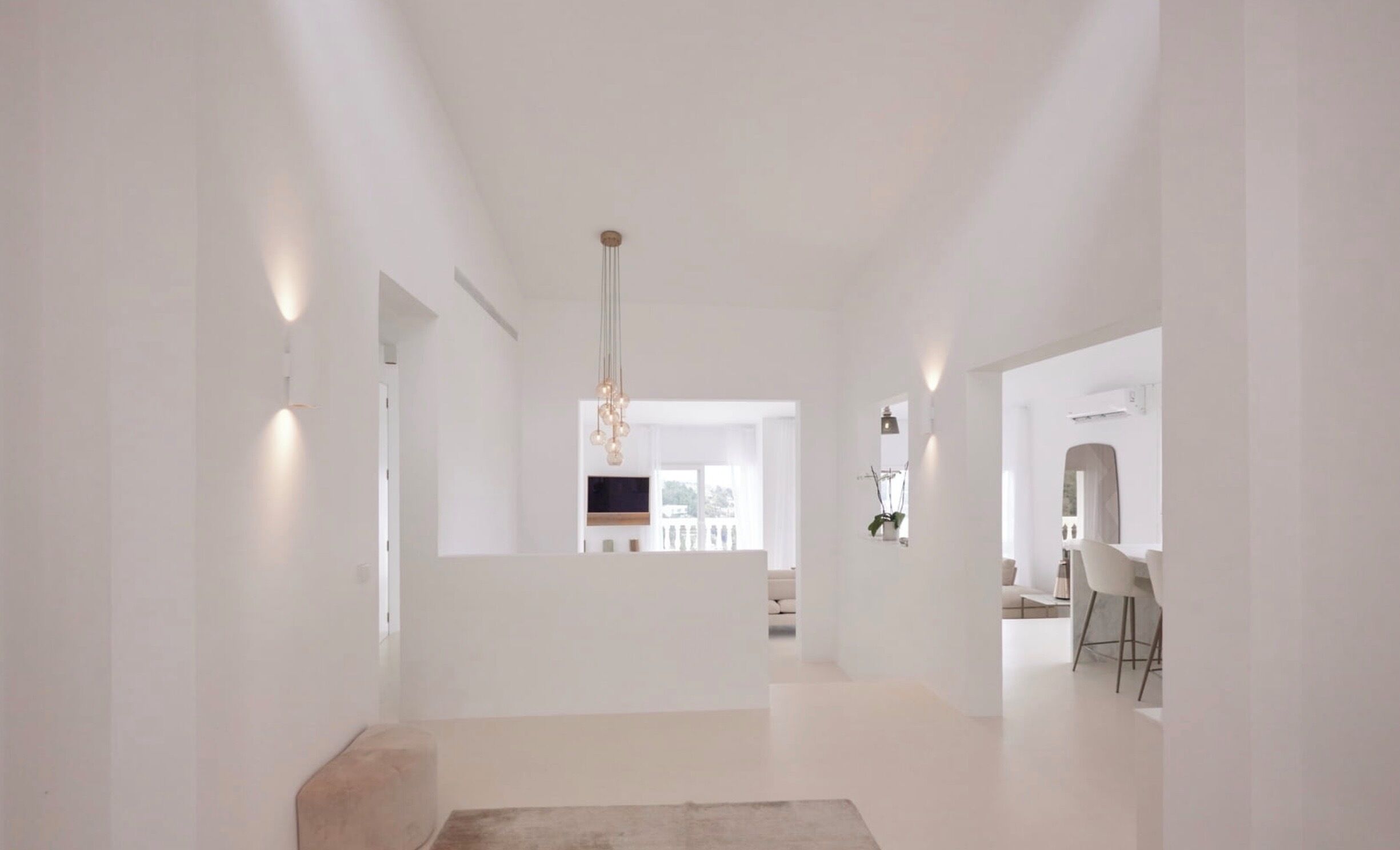 Interior espaçoso e moderno com design minimalista, apresentando uma luminária central, área de estar e vista para uma varanda.