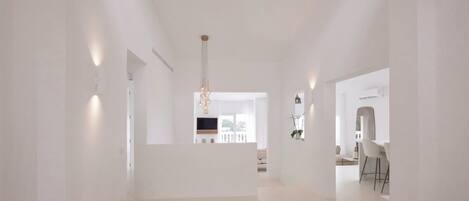 Interior espaçoso e moderno com design minimalista, apresentando uma luminária central, área de estar e vista para uma varanda.
