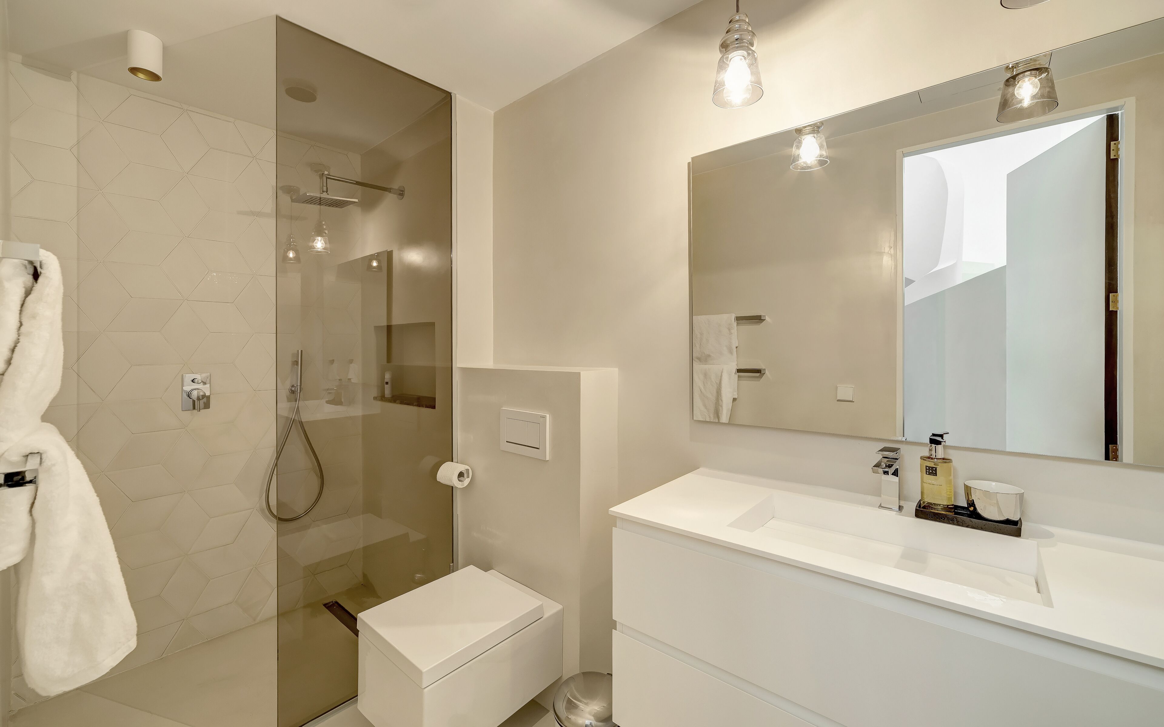A modern bathroom with a glass-enclosed shower, a white vanity, and a large mirror.