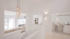 Een modern interieur met een trap, een zithoek met uitzicht en een eethoek met barstoelen.