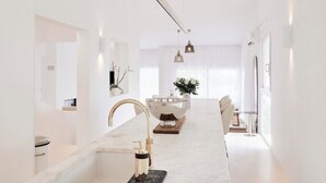 Een moderne, minimalistische badkamer met een grote spiegel, een gouden kraan en een marmeren aanrecht.