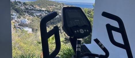 Una cyclette con display digitale, situata in una stanza con vista sul paesaggio costiero.