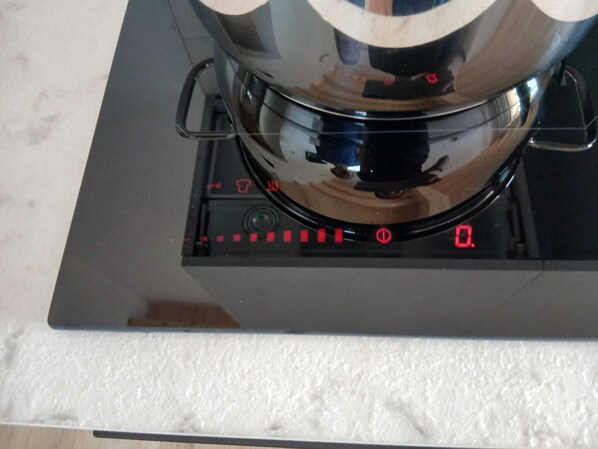 A kitchen with a stove, a pot, and a digital control panel.