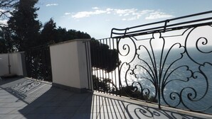 A balcony with a metal railing and a view of the sea.