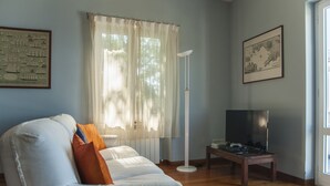 A living room with a white sofa, a floor lamp, and a television on a wooden stand.