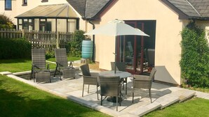 Une maison dotée d’un patio aménagé avec du mobilier d’extérieur et une porte vitrée donnant sur une véranda couverte.