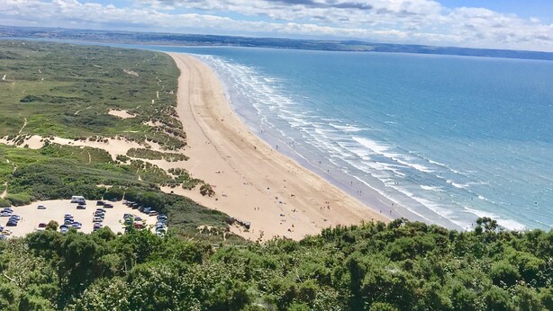 Une plage avec un espace de stationnement et une vue sur l’océan.