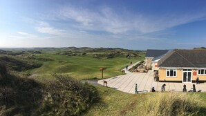Un bâtiment doté d’une entrée pavée et offrant une vue sur un terrain de golf.