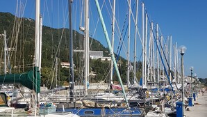 A marina with multiple boats docked, a clear sky, and a hilly landscape in the background. - Spacious,holiday house close to beach ideal for a group of friends or family (Gastouri)