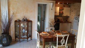 A dining area with a wooden table set for four, surrounded by white chairs. A cabinet with glass doors displaying various dishes and a potted plant are visible. - PEACE AND PRIVACY AT HOME "Il CORBEZZOLO" (Poggio Catino)