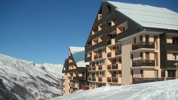 Un hôtel à plusieurs étages, doté de balcons, avec une montagne enneigée en toile de fond.