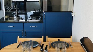 Un coin repas avec une table en bois dressée pour deux personnes, agrémentée d’assiettes, de couverts et de verres.
