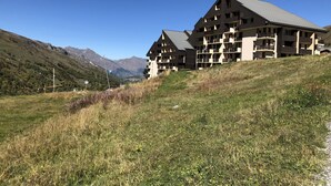 Un immeuble à plusieurs étages, doté de balcons, qui se dresse sur fond de montagnes.