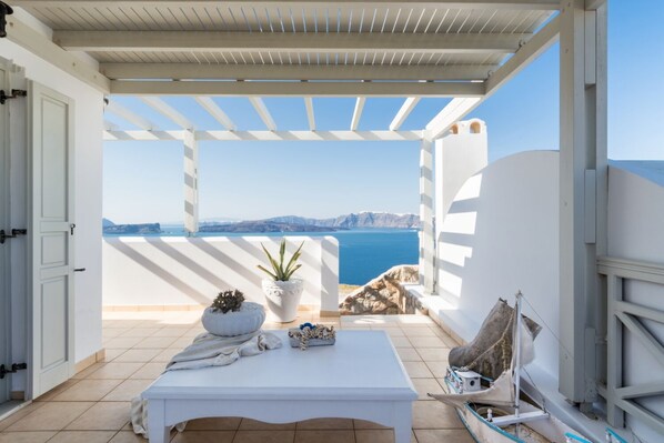 A balcony with a white table, potted plants, and a view of the sea and mountains. - 5 bedroom luxury villa with pool and stunning sea views and amazing sunsets (Akrotiri Thiras)