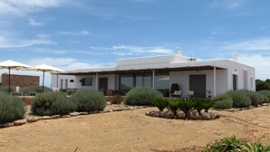 A modern house with a patio area, surrounded by landscaped greenery and a clear sky. - HOUSE IN PARADISE ISLAND (El Pilar de la Mola Formentera)