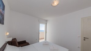Un dormitorio con una cama, una silla, una puerta y una ventana.