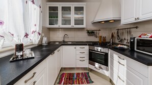 Una cocina moderna con armarios blancos, encimera negra, horno de acero inoxidable y microondas.