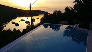 A infinity pool with a view of boats on a body of water at sunset. - A1 Large, Two bedroom Apartment of the Villa Sonia and  Teo, Hvar, Croatia (Hvar)