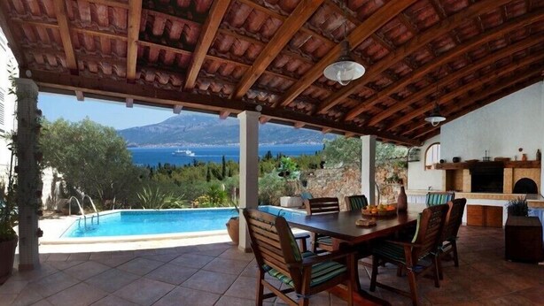 Un patio techado con piscina, zona de comedor y chimenea de piedra.