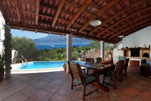 Un patio couvert avec une piscine, un coin repas et une cheminée en pierre.