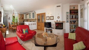 Una sala de estar con sofás rojos, una mesa de centro de cristal, un televisor y una estantería.