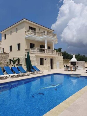 Un bâtiment à deux étages doté d’une piscine, de chaises longues et d’un espace barbecue.
