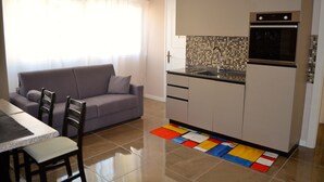 A compact kitchen with a built-in oven, a dining area with a table and chairs, and a colorful rug. - Charming appartment Ideal for 4 guests, in San Pietro, 2 bedrooms & 2 bathrooms  (Roma)