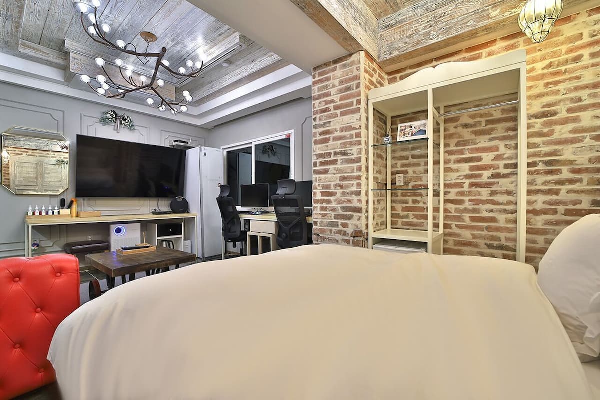Un dormitorio moderno con una cama grande, un escritorio, una silla, un televisor y un armario.