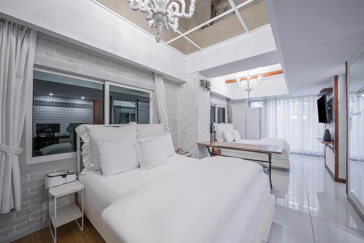 Una habitación de hotel moderna con una cama grande, una mesita de noche, un espejo y un televisor.
