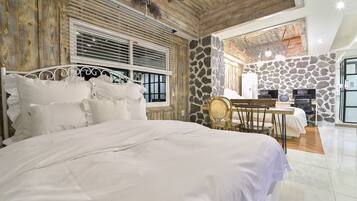 Un dormitorio con una cama grande, paredes de madera, una pared de acento de piedra y una zona de comedor con mesa y sillas.