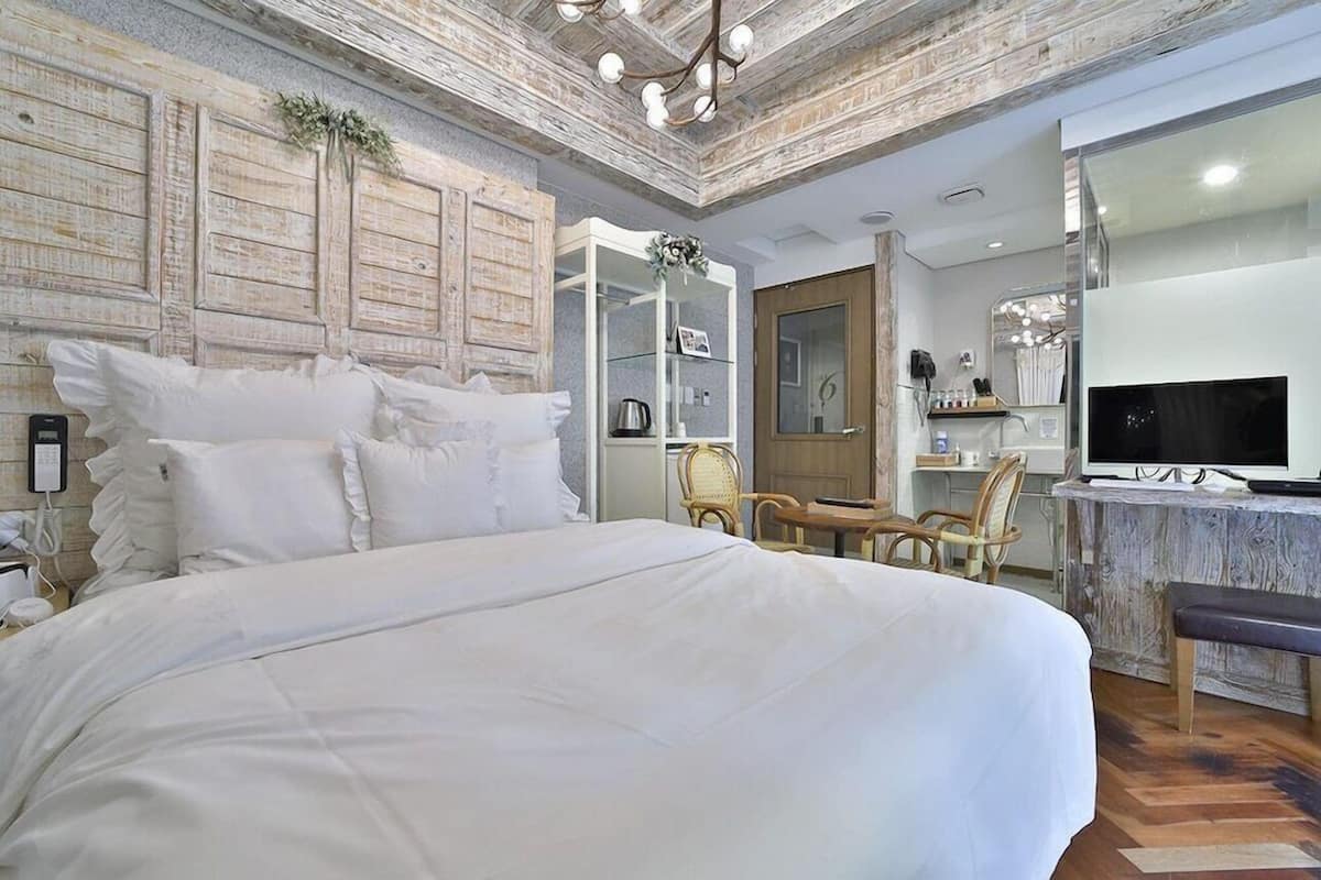 Un dormitorio con una cama grande, un armario de madera, un televisor y un escritorio con sillas.