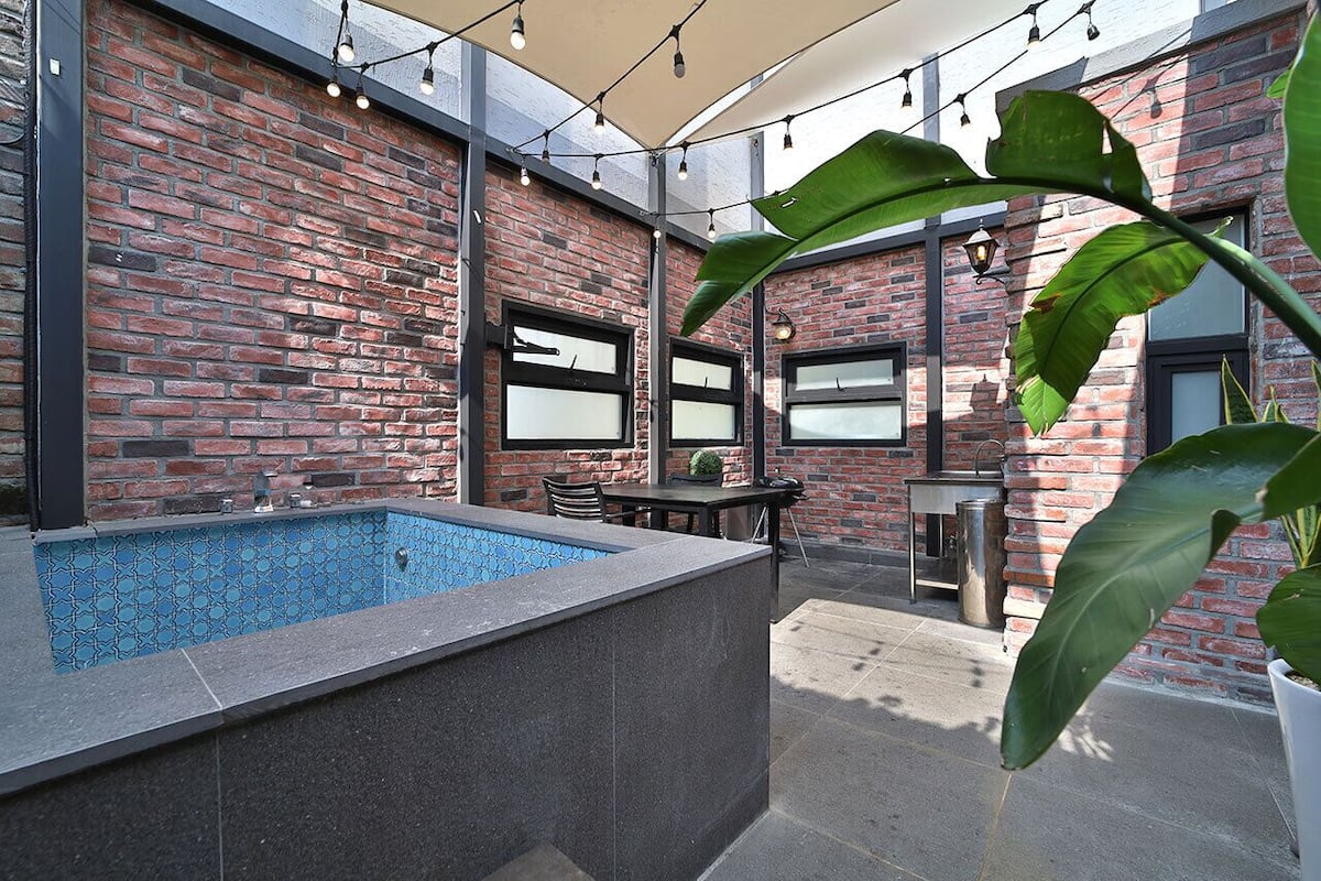 Un edificio de ladrillo con piscina, mobiliario exterior e iluminación con luces.
