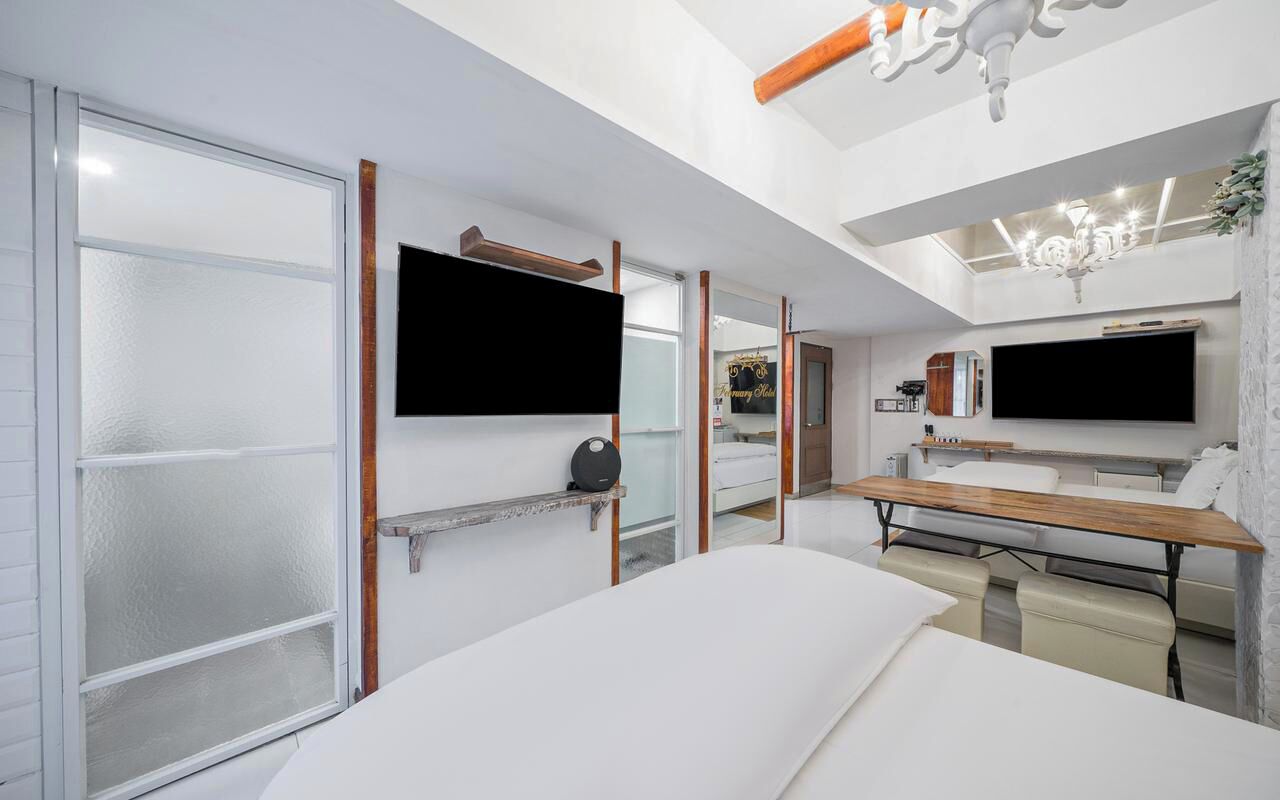 Una habitación de hotel moderna con una cama grande, un escritorio, un televisor de pantalla plana y un separador de vidrio.