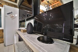 Une cuisine moderne équipée d’un grand téléviseur à écran plat, d’un réfrigérateur, d’un four à micro-ondes et d’un évier.