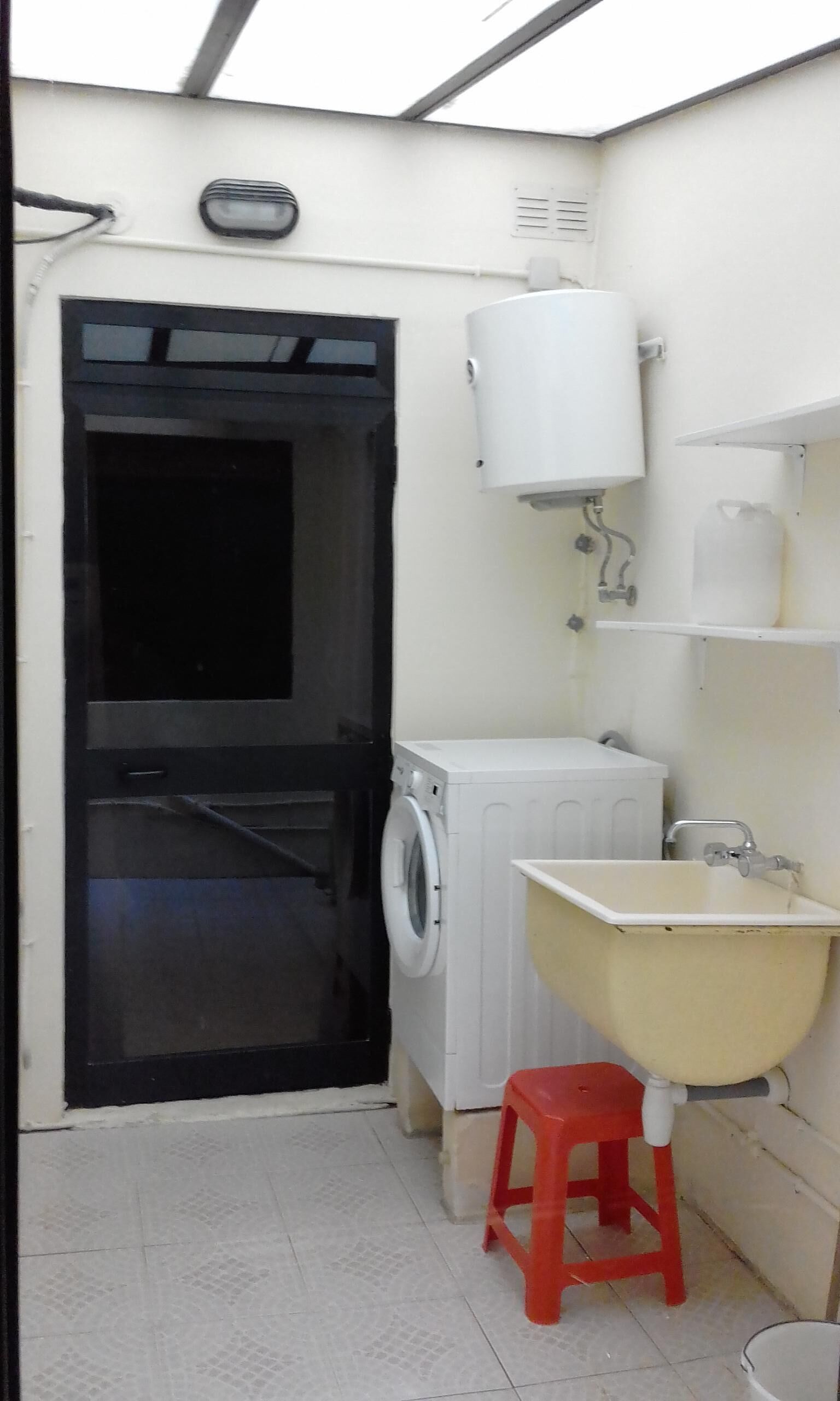 A compact bathroom with a washing machine, a sink, and a toilet.