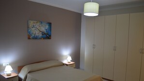 Une chambre à coucher avec un lit, des lampes de chevet, une armoire et un tableau au mur.