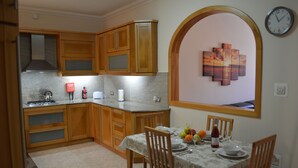 Une cuisine avec des meubles de rangement en bois, une cuisinière à gaz et une table à manger mise pour deux personnes.