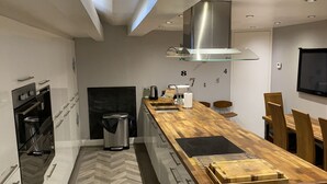 A modern kitchen with a wooden countertop, built-in oven, and a herringbone-patterned floor. - 5* Barn Conversion c/w hot tub, sauna, games room, 1/4 acre enclosed games (Stocksfield, Northumberland)