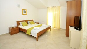 Ein Schlafzimmer mit Bett, Nachttischen, Fernseher und Kleiderschrank.