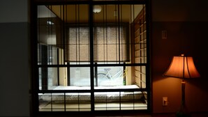 A room with a bed, a lamp, and a window with a bicycle visible through the bars. - Kyoto Guest House Nanni Saiin (Kyoto)