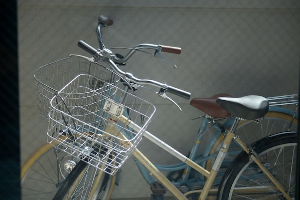 A bicycle with a basket and a brown seat, parked against a wall.