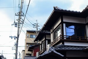 A traditional Japanese building with multiple stories, wooden balconies, and a tiled roof. - Kyoto Guest House Nanni Saiin (Kyoto)