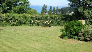 Un giardino erboso con vista sul mare e sugli alberi.