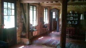 A rustic room with exposed wooden beams, a fireplace, and a collection of dishes on a shelf. - Charming House, Edge of the Golf, Sea, Countryside, Peaceful (Seine-Maritime)