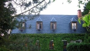 Una casa con techo inclinado, varias ventanas y un porche cubierto.
