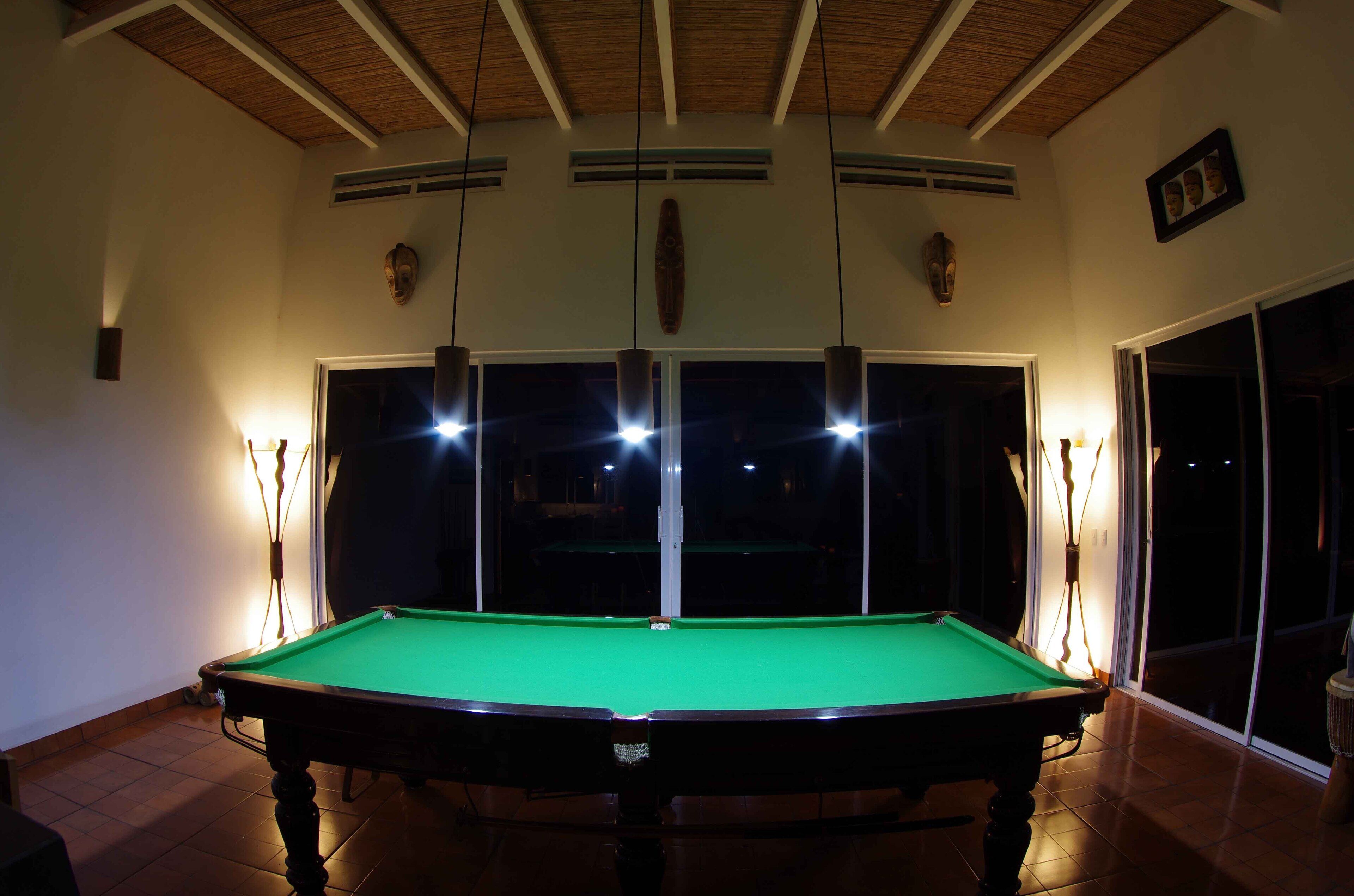 Ein Billardtisch in einem Raum mit hoher Decke und großen Fenstern.
