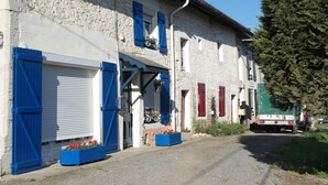 A row of stone buildings with blue shutters and a truck parked in front.