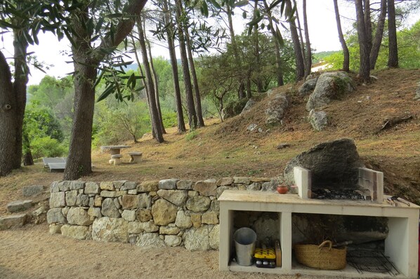A stone wall, a stone bench, and a grill area with a stone table and a basket.